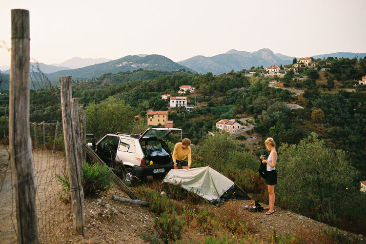 Preparing camp with Fiat Panda and tent with Italian hillside background 