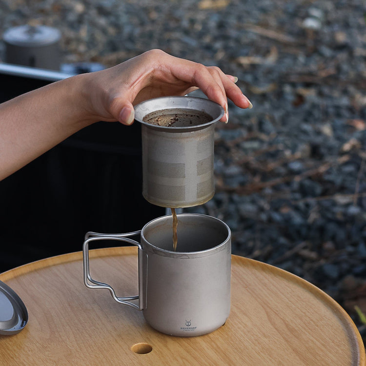 
                  
                    SilverAnt Titanium Double Wall Mug 300ml/10.14fl oz Folding Handles - Actual product photo, in-use, real life still, lifestyle shot, lifting filter to separate coffee grounds from drink 
                  
                