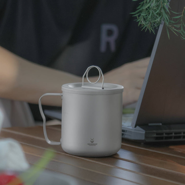 
                  
                    SilverAnt Titanium Double Wall Mug 300ml/10.14fl oz Classic Handles - Actual product photo, real life setting, in use, working outdoors, beside a laptop, lifestyle shot
                  
                