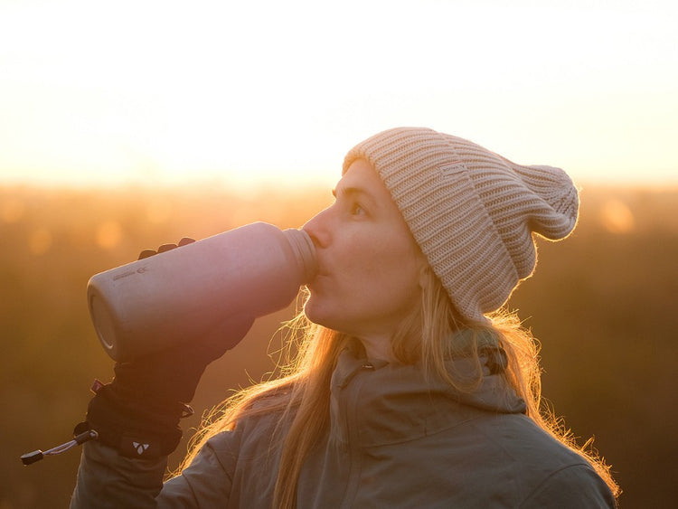 Person drinking from a thermos at sunset
