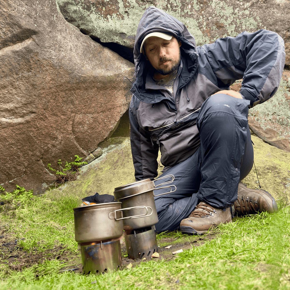 Ultralight 3-Piece Titanium Camping Cookware Set - In-Use photo (Camp cooking, clearing, rocks in background, man wearing camping clothes and jacket)