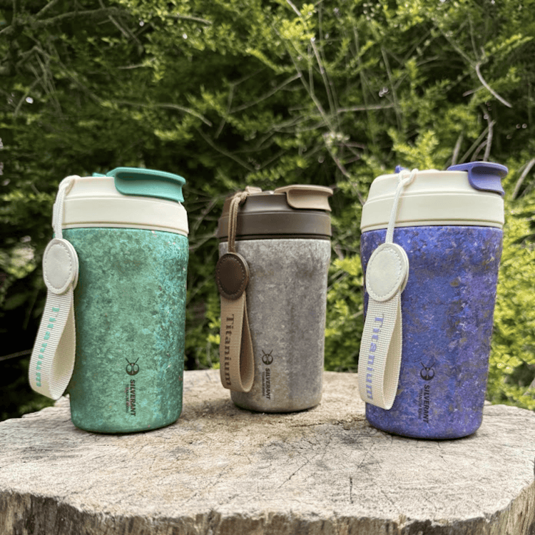
                  
                    SilverAnt Ultralight Crystallized Titanium Insulated Travel Coffee Mug with Lid 400ml/14 fl oz Classic Silver, Light Green, and Ocean Blue on a tree stump, outdoors photo, real life still, lifestyle shot
                  
                