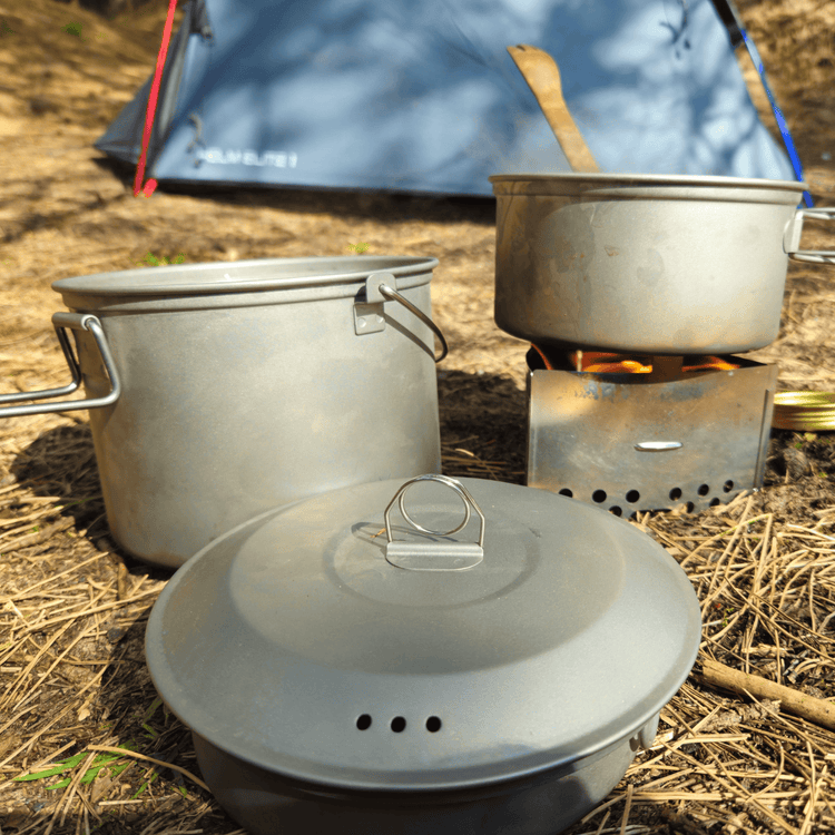 
                  
                    SilverAnt Ultralight Large Titanium Camping Pot with Lid & Bail Handle 2L/67.63 fl oz - In-Use (3-Piece Titanium Cookware Set laid out in grass, cooking outdoors, camp cooking)
                  
                