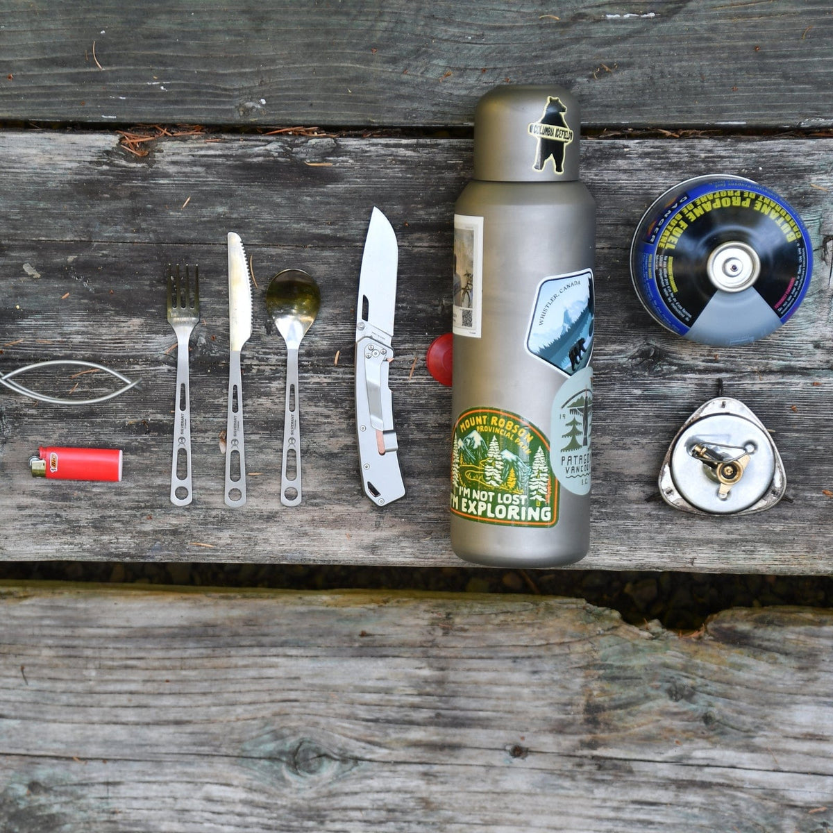 SilverAnt Ultralight Large Titanium Water Bottle With Titanium Cup - In-Use (Actual product photo, laid on top of old wooden outdoors camping table with various other essential camp gear)