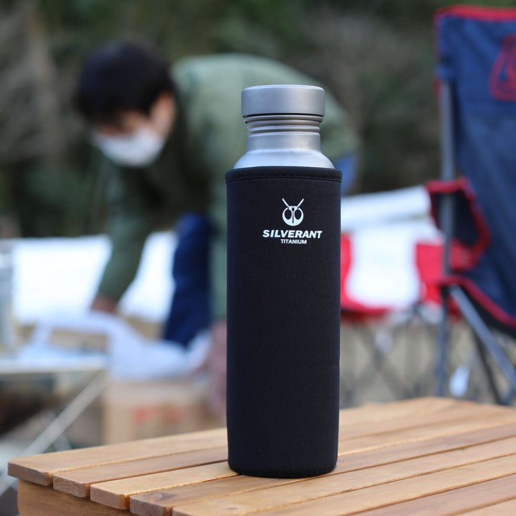 
                  
                    SilverAnt Ultralight Round Titanium Water Bottle - In-Use (Actual product photo, on top of wooden table, black thermal sleeve, silverant branding)
                  
                