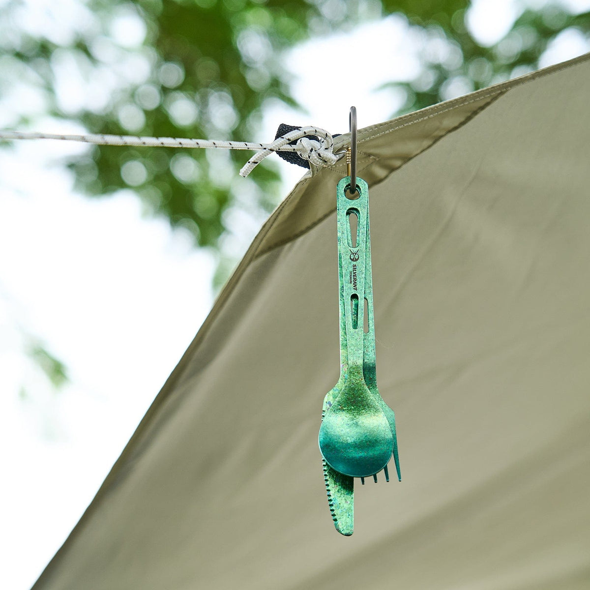 SilverAnt Ultralight Titanium 3-Piece Cutlery Set (Knife, Fork, and Spoon) Anodized Green - actual product photo, real life, outdoors setting, hanging on a tent