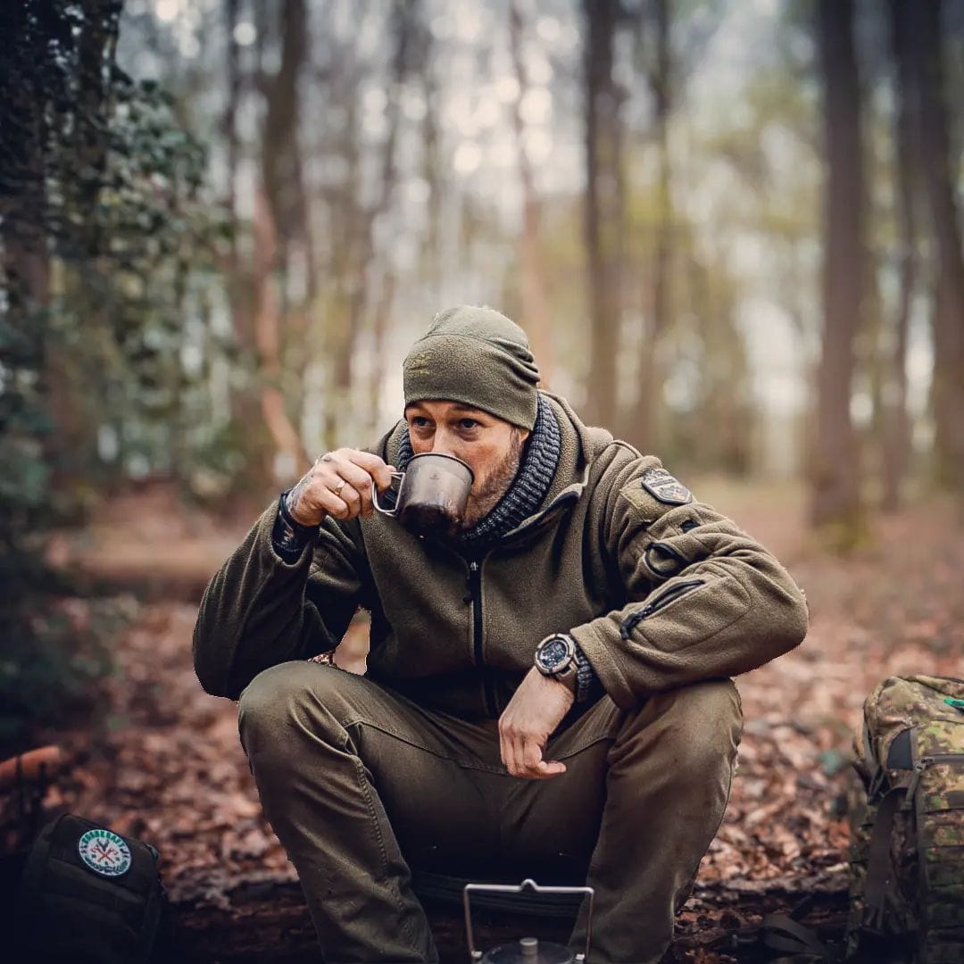 SilverAnt Ultralight Titanium Cup With Lid 4 Sizes - Actual product photo, lifestyle shot, in use, on hand, man drinking from titanium cup while sitting on a felled tree log