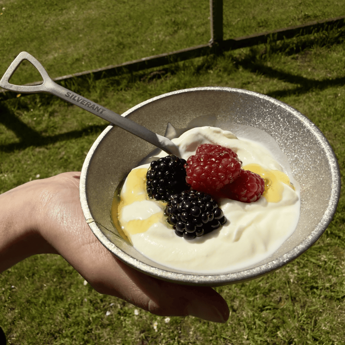SilverAnt Ultralight Titanium Double-Wall Bowl Crystallized - In-use (lifestyle, outdoors, eating fruits, held by hand, grass, camping)