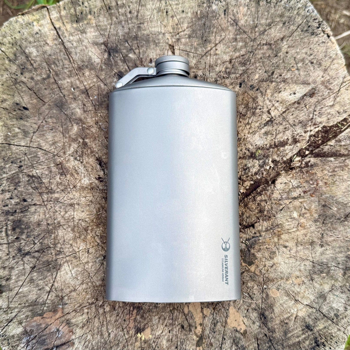 SilverAnt Ultralight Titanium Hip Flask & Funnel - 450ml/15.22 fl oz (actual product photo, laid flat on a tree stump, top view)