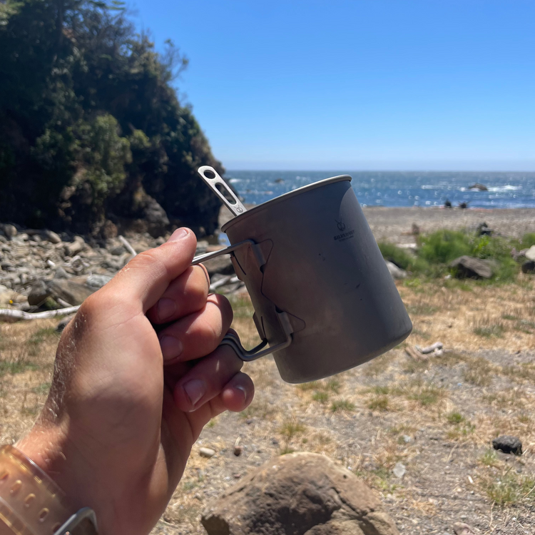 
                  
                    SilverAnt Ultralight Titanium Multi-Fuel Stove & Cup Kit - In-Use (held in front of camera, beach background, outdoors setting, day)
                  
                