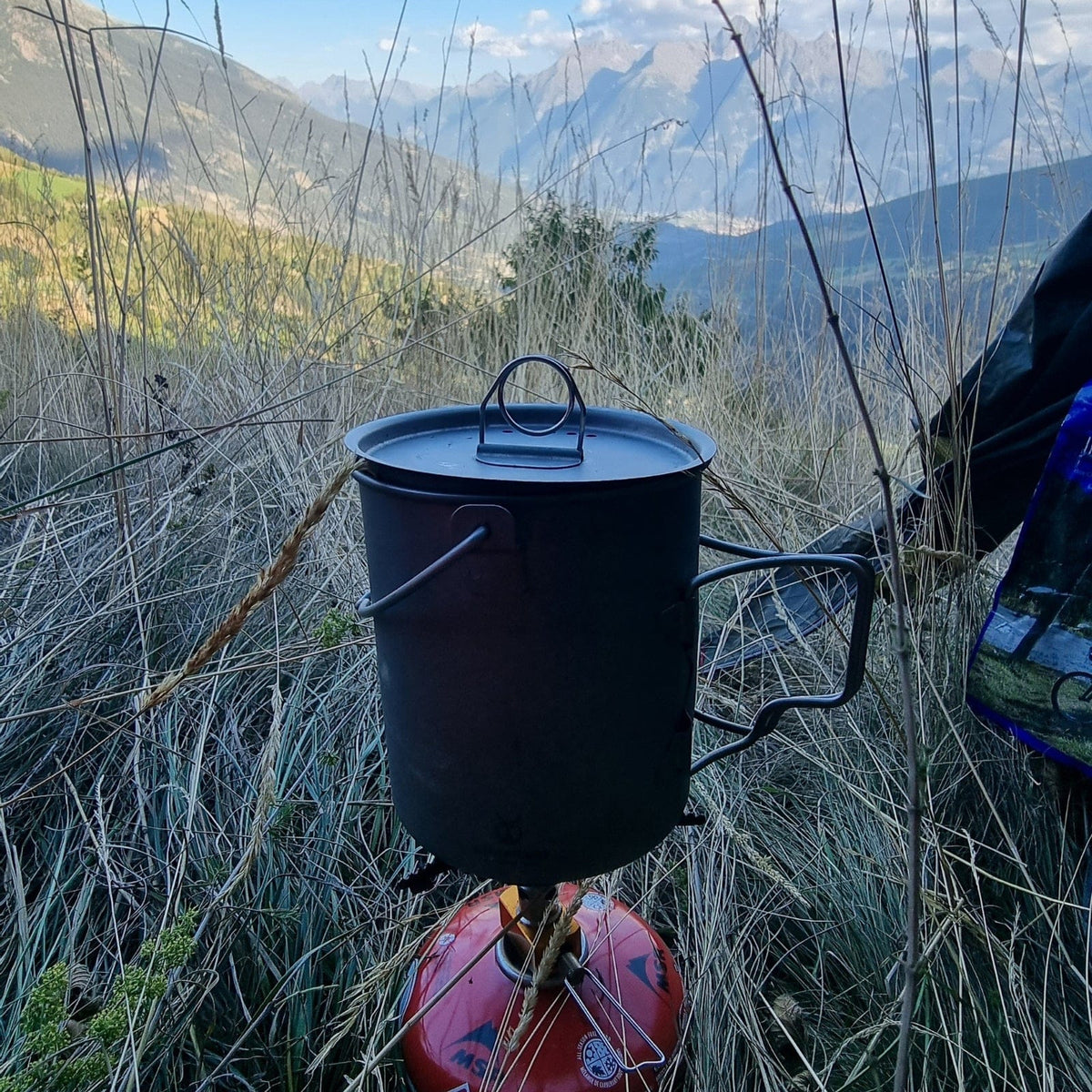 SilverAnt Ultralight Titanium Pot 750ml/25 fl oz with Lid and Bail Handle - In-Use (Cooking with gas stove, tall grass, mountain view)