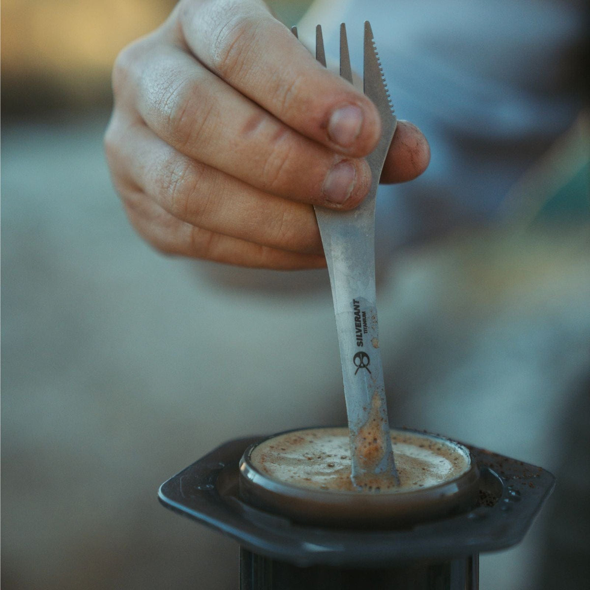 SilverAnt Ultralight Titanium Spork 3-in-1 Knife Fork Spoon - on hand, in use, stirring coffee with spoon end