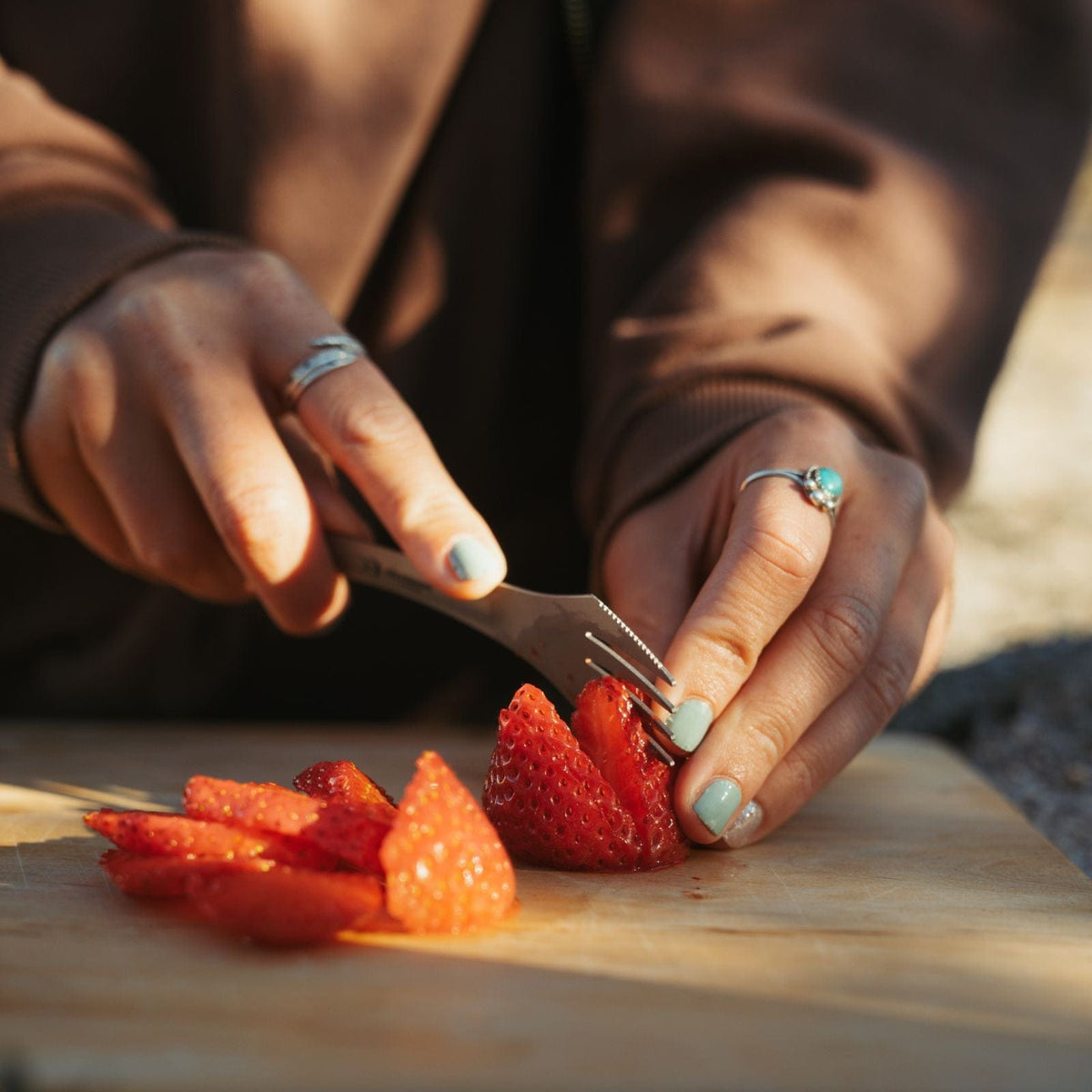 SilverAnt Ultralight Titanium Spork 3-in-1 Knife Fork Spoon - actual product photo, in use, on hand, slicing strawberries