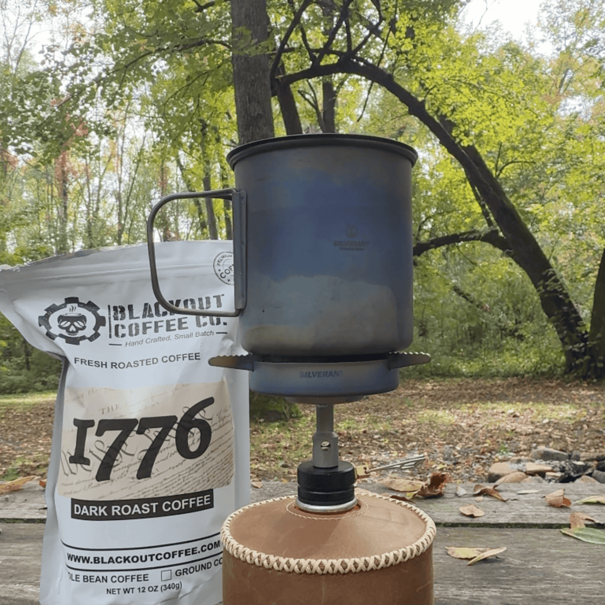 SilverTi Ultralight Titanium Gas Stove - Actual product photo, with Silverant titanium cup on top, unignited, with coffee pouch in background, nature, outdoors