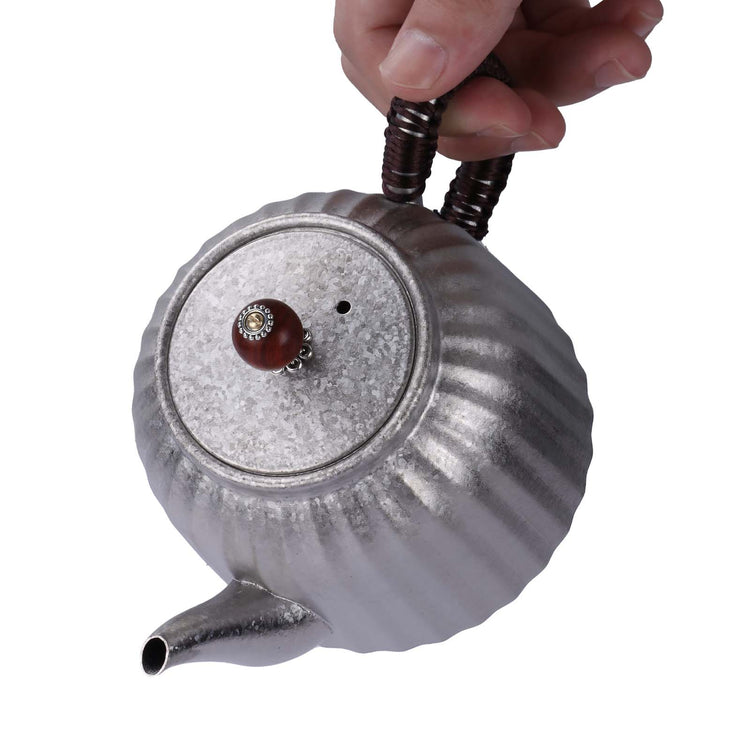 
                  
                    SilverAnt Ultralight Titanium Pour Over Tea Pot with Black Braided Handle and Ornate Wooden Lid Handle - pouring position, on hand
                  
                