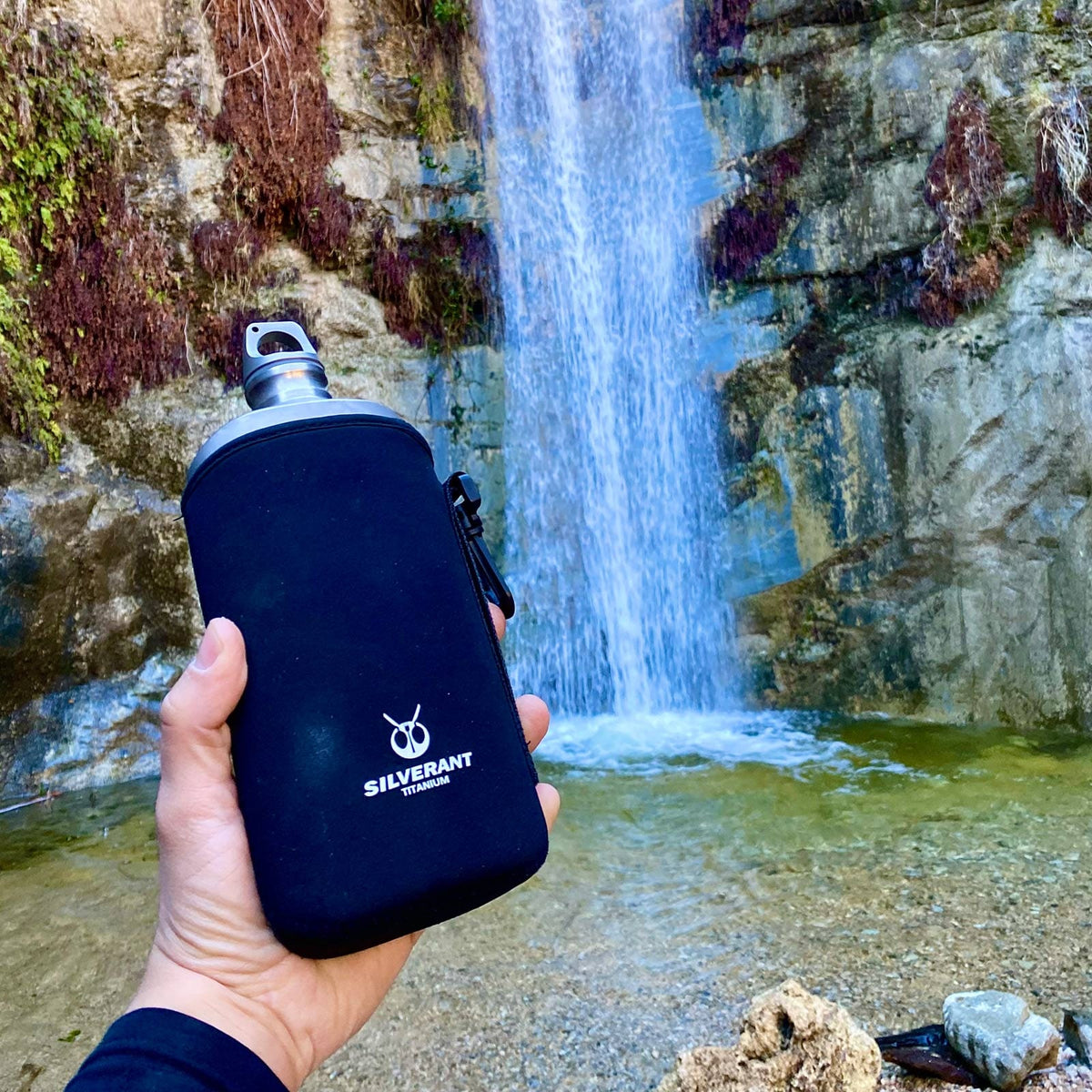 SilverAnt Ultralight Titanium Water Bottle 800ml/28.16 fl oz (Slim Sandblasted) - In-Use (held in front of waterfall, thermal sleeve, silverant branding)